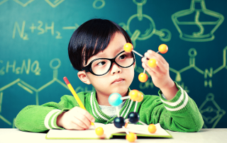 Child with glasses holding a model of an atom