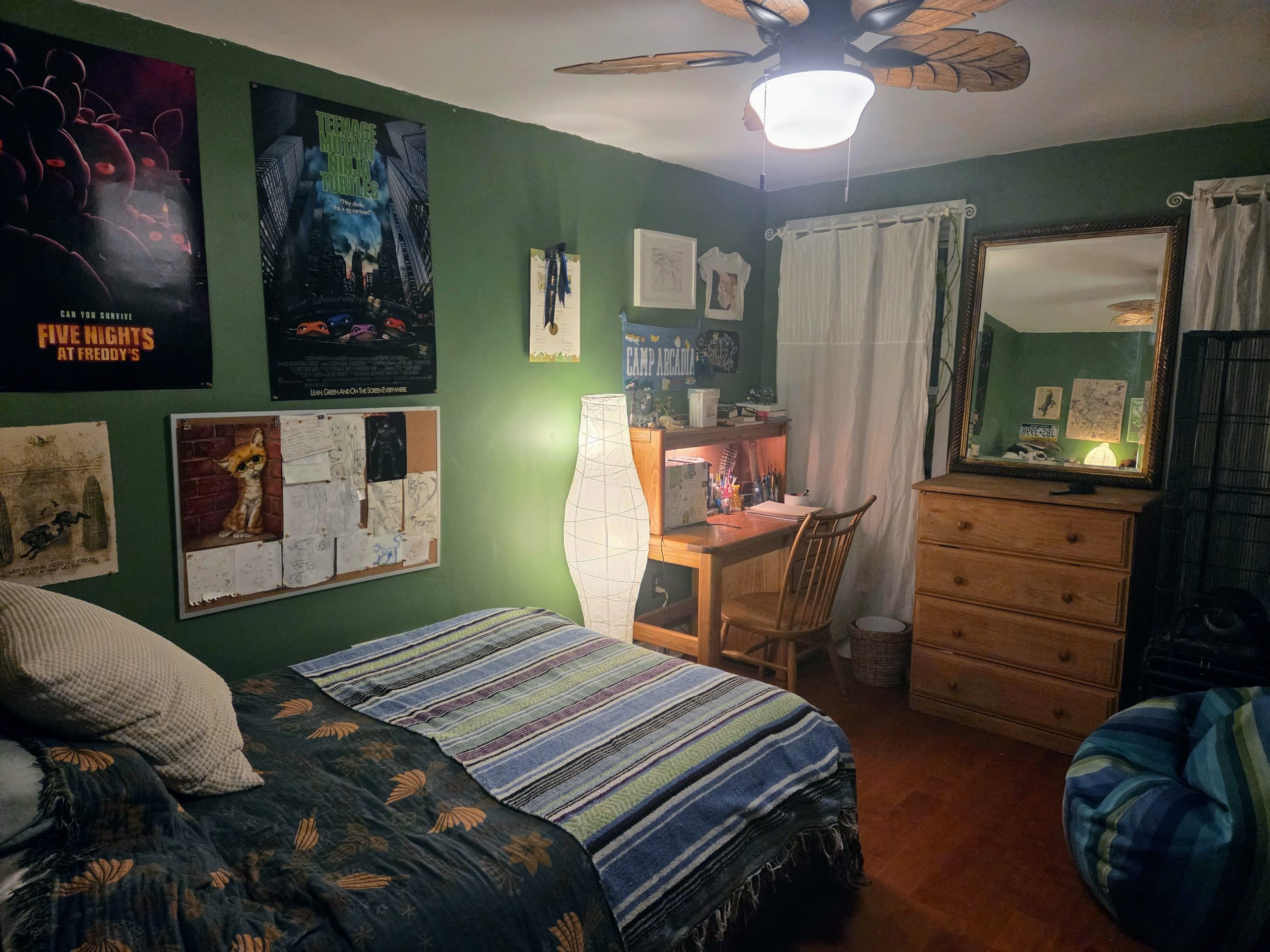 Teenager's bedroom with green walls striped blanket and posters on the walls.
